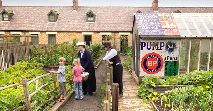 costumed staff with children in the miners cottages garden at Beamish Museum